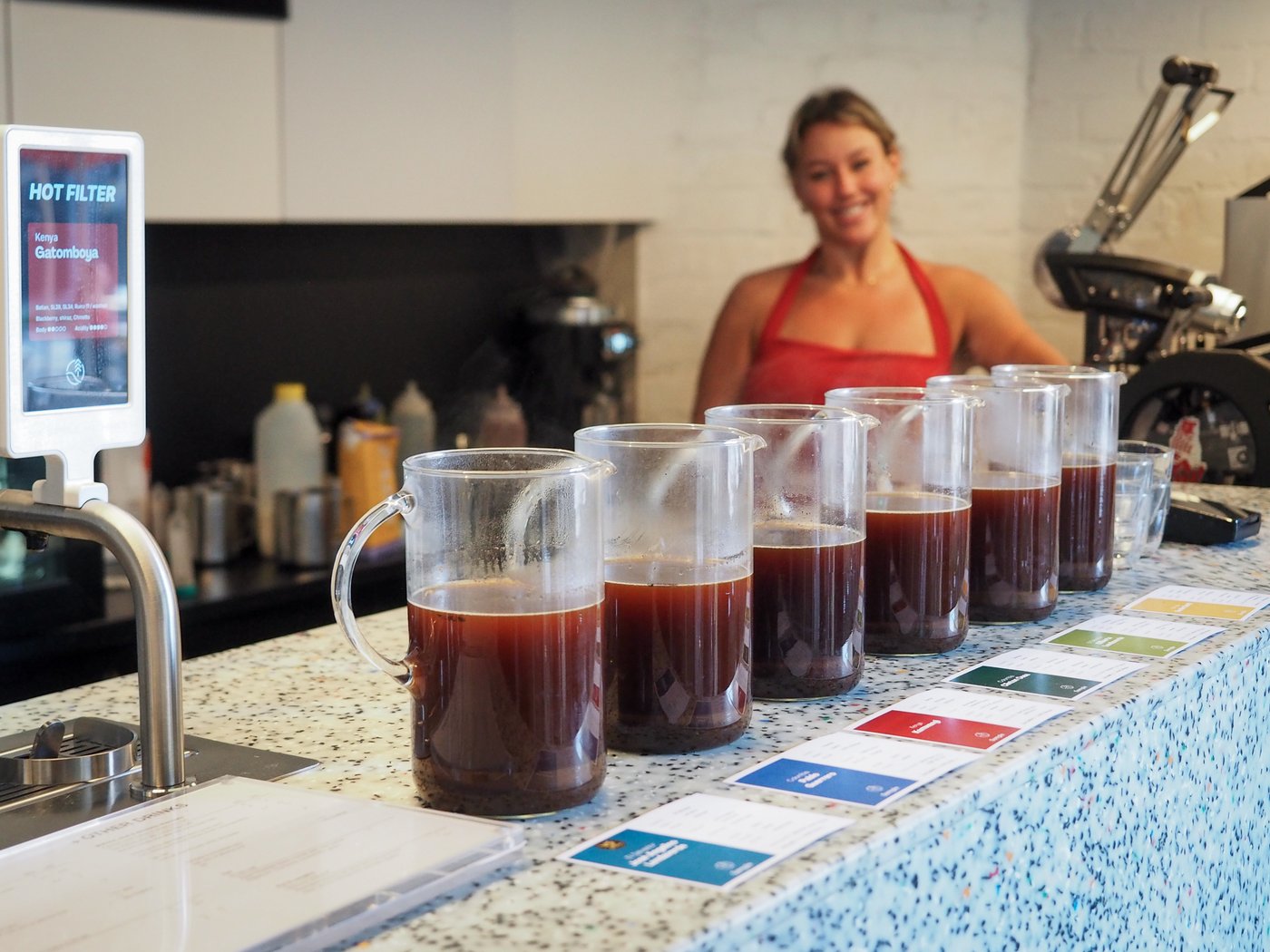 The coffee lineup in one of our tasting sessions at Surry Hills, with a staff smiling in the backgroud.