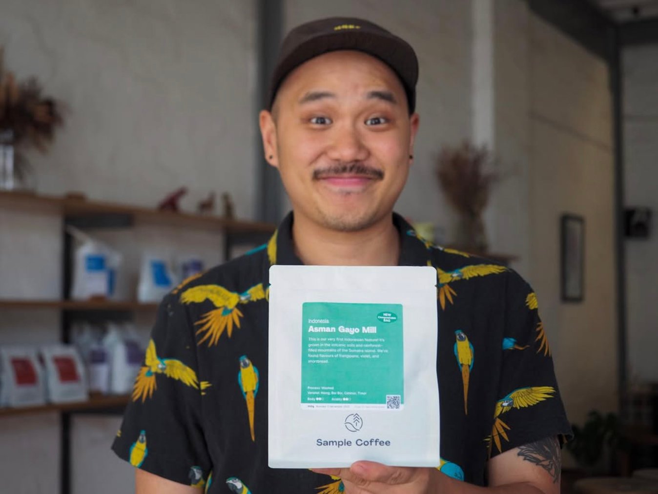 A staff member holding a Sample Coffee bag.