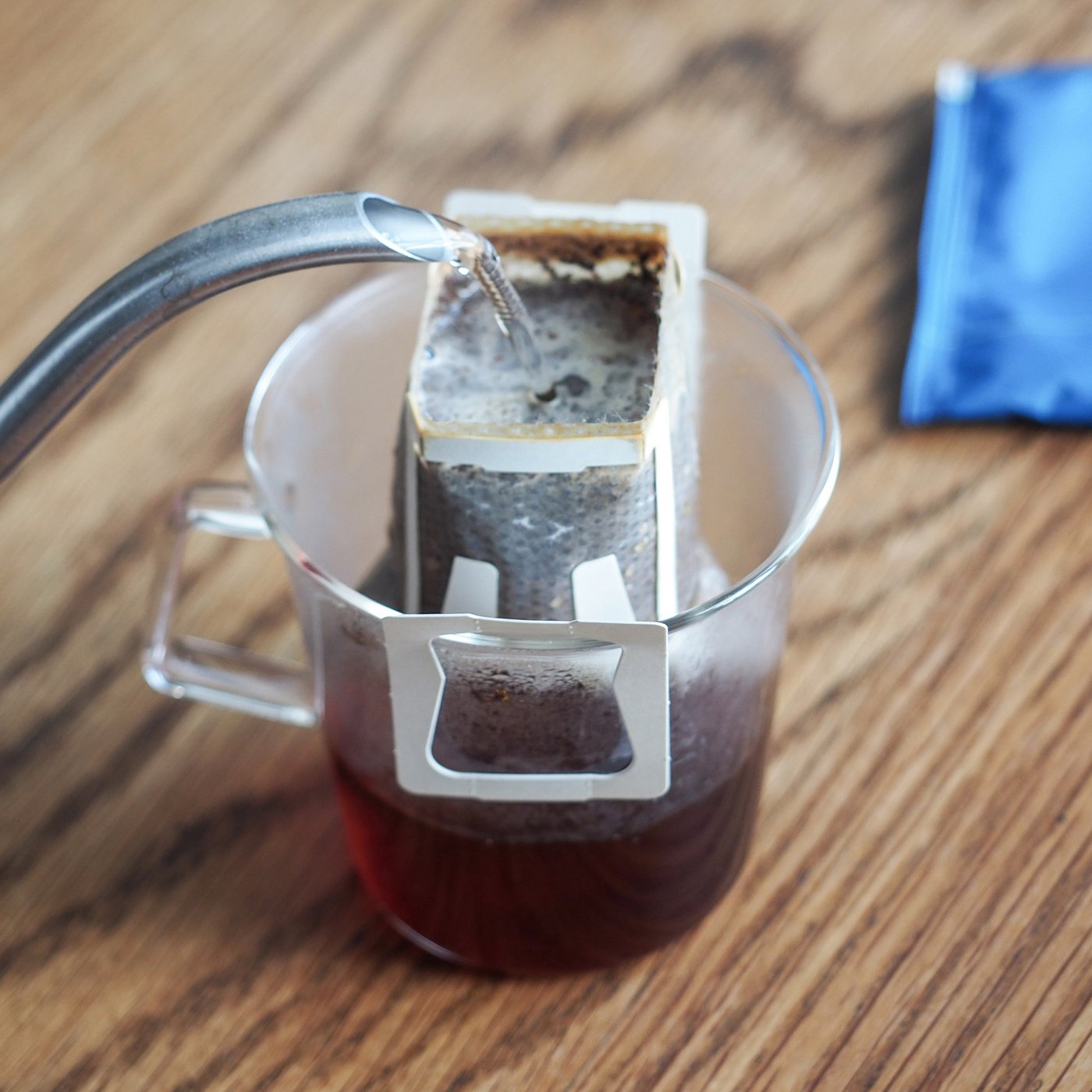 Water poured onto a brew bag in a transparent mug.